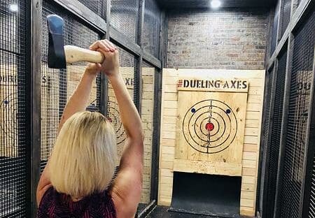 Women holding an axe above her head ready to throw it at an axe throwing target