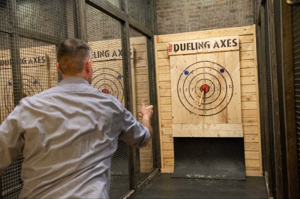Man using balance and weight distribution techniques to hit a bullseye while axe throwing