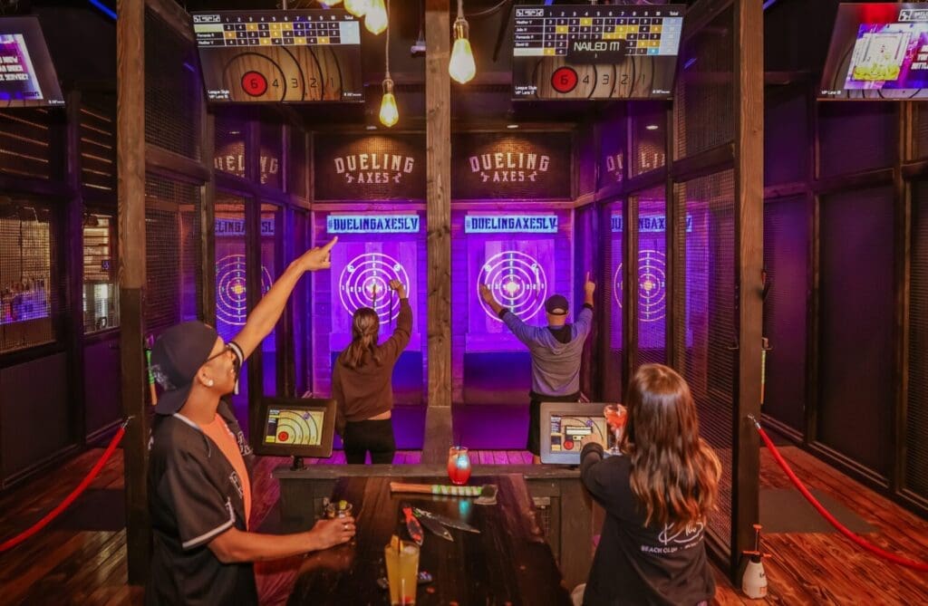4 friends enjoying cosmic axe throwing and knife throwing while drinking premium cocktails